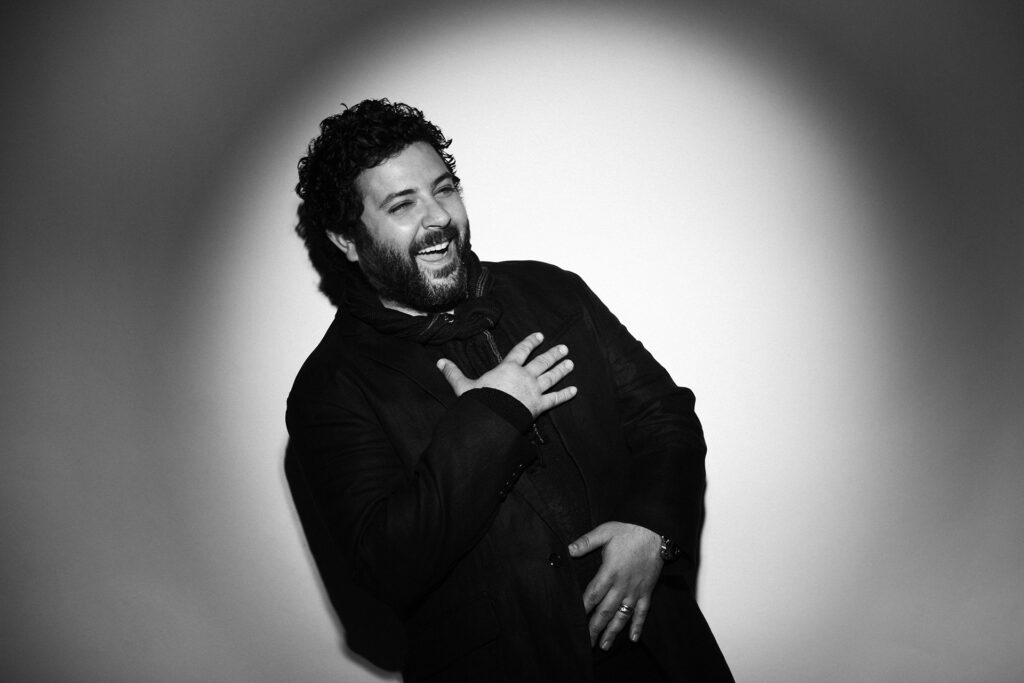 Rino Marra, famous hair stylist, laughing and posing in a professional black-and-white portrait, captured by Visionary Headshots.